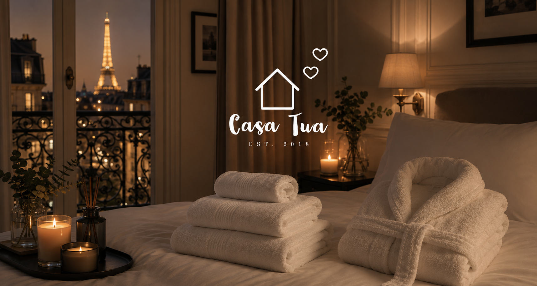 Habitación de hotel de lujo inspirada en París con ropa de cama blanca, bata y toallas de algodón blanco de Casa Tua, velas encendidas y vista a la Torre Eiffel.
